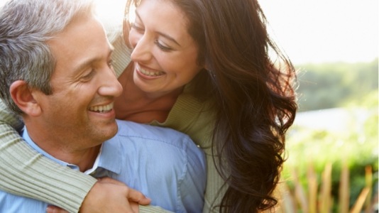 Smiling man and woman embracing outdoors
