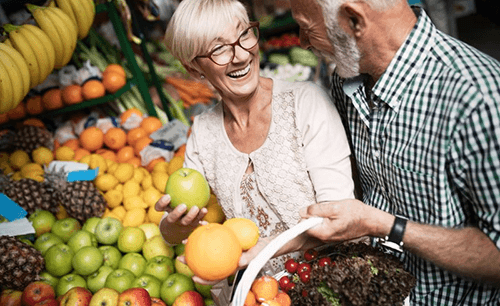 a couple with dental implants shopping for healthy food