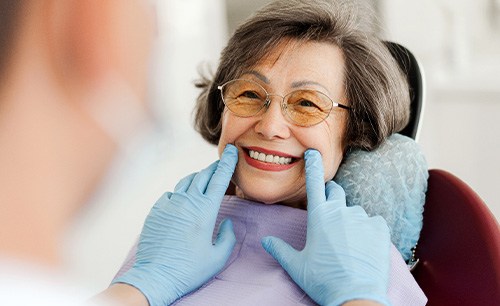 Dentist with blue gloves looking at senior woman's smile