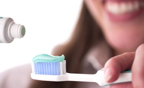 Lady applies toothpaste to brush