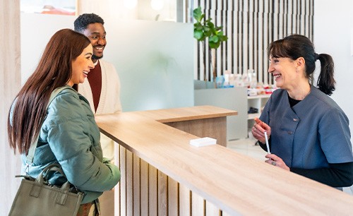 Dental receptionist talking to smiling couple