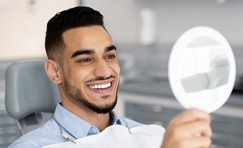 Man smiling at reflection in mirror in treatment chair