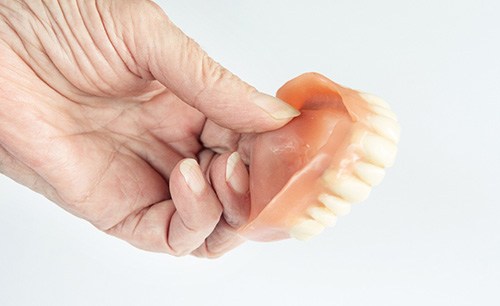 Close-up of a hand holding a denture