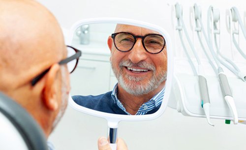 a patient checking his smile with a mirror