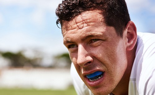 Sweaty man outside with blue mouthguard over upper arch