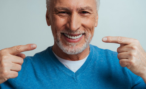 A handsome senior pointing out his fully-restored smile