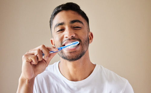 Man smiling while brushing his teeth