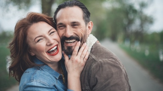 Laughing man and woman hugging outdoors