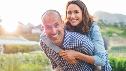 Man and woman in blue shirts smiling outdoors