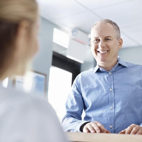 Dental patient checking in at dental office reception desk