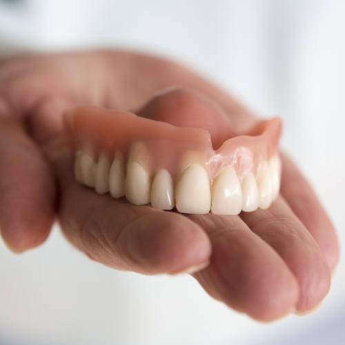 Hand holding a removable denture