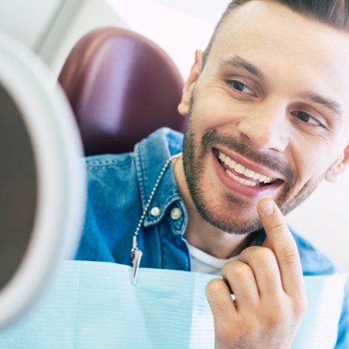 Man with tooth colored filling pointing to smile