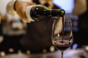 person pouring a glass of red wine