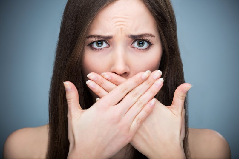 Woman with bad breath covering her mouth