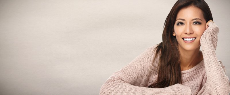 a young woman wearing a cream-colored sweater and showing off her beautiful smile