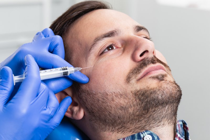 a young man having Botox injected during a session to eliminate crow’s feet