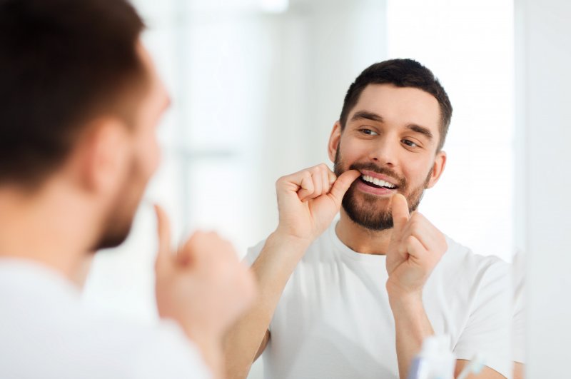 man flossing in the mirror