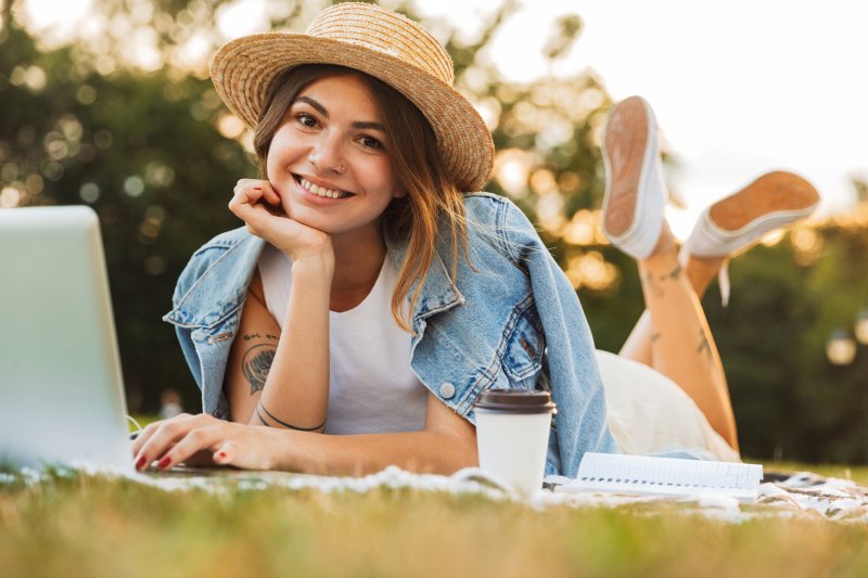 Woman smiling while working on laptop at the park