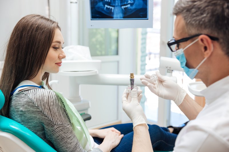 Dentist showing dental implant in Columbia to woman