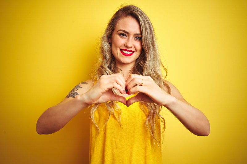 person smiling and making a heart with their hands