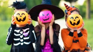 three kids holding jack o lantern baskets in front of their faces
