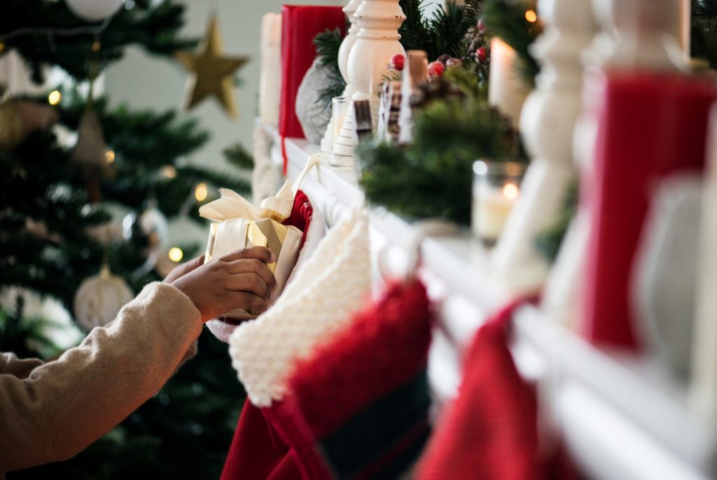 Child grabbing present from stocking hung on the fireplace