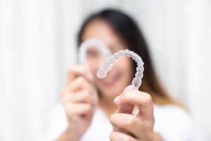 Woman holding up her SureSmile aligners