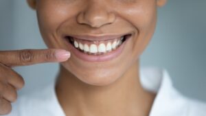 Person pointing to healthy smile and gums.